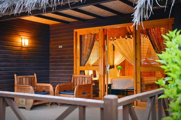 Außenbereich des Bandos Maldives Hotels mit zwei Holzstühlen und einer offenen Tür zum Schlafzimmer.