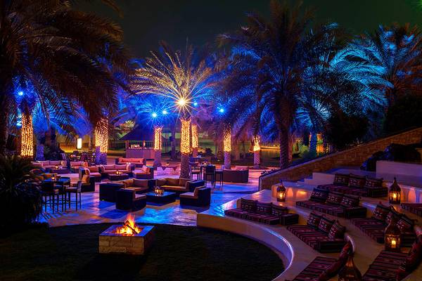 Außenbereich des Sheraton Abu Dhabi Hotel & Resort mit beleuchteten Palmen und Sitzgelegenheiten