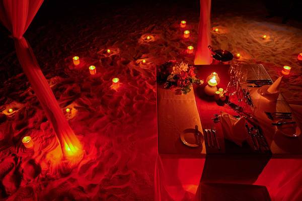 Ein romantisches Abendessen am Strand der Bandos Maldives mit brennenden Kerzen.
