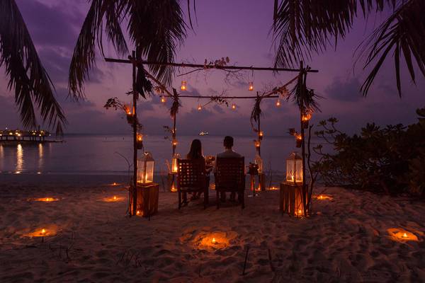 Zwei Personen genießen ein Abendessen unter Sternen auf einem Strand