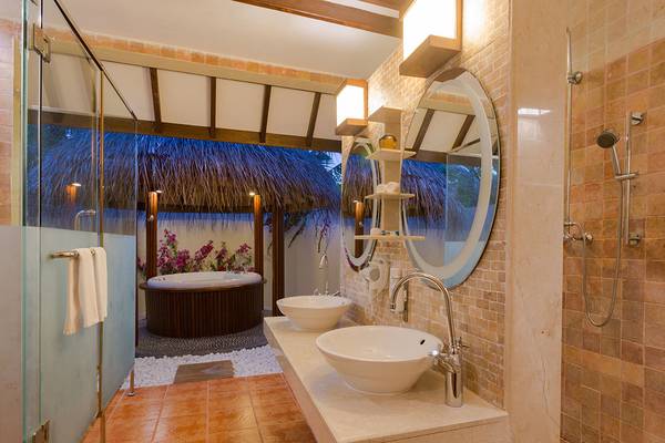 Badezimmer im Bandos Maldives Hotel mit Badewanne, Dusche und zwei Waschbecken.