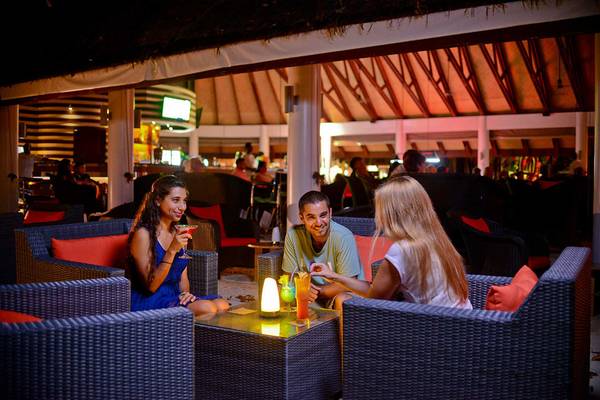 Drei Personen sitzen in der Abendlounge im Bandos Maldives und unterhalten sich.