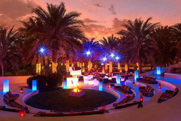 Loungebereich des Sheraton Abu Dhabi Hotel & Resort bei Nacht mit beleuchteten Palmen und Feuerstelle.