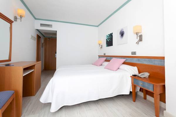 Doppelbettzimmer im Timor Hotel mit weißem Bettlaken, zwei pinken Kissen und Nachttischen.