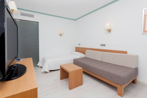 Modernes Zimmer im Timor Hotel mit Bett, Fernseher und Sofa.