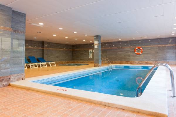 Ein Poolbereich im Timor Hotel mit Liegen und einem kleinen Whirlpool.