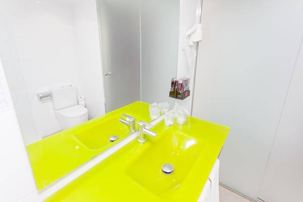 Badezimmer im Timor Hotel mit einem neon gelben Waschbecken und Spiegel.