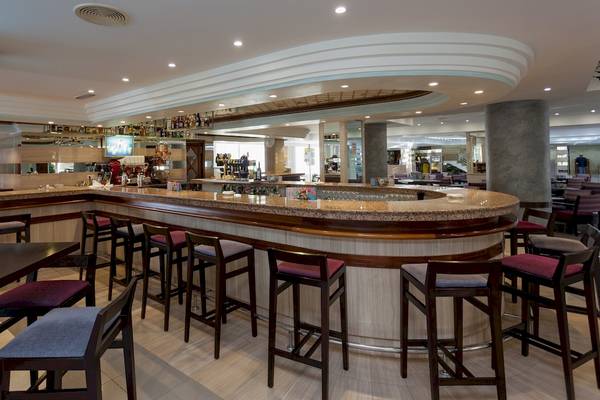 Innenansicht der Bar und Rezeption des Timor Hotels mit gerundeter Theke, Stühlen und Tischen.