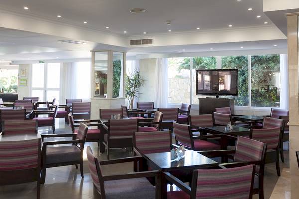 Innenansicht des Restaurants des Timor Hotels mit Tisch, Stühlen, Fernseher und Pflanzen.