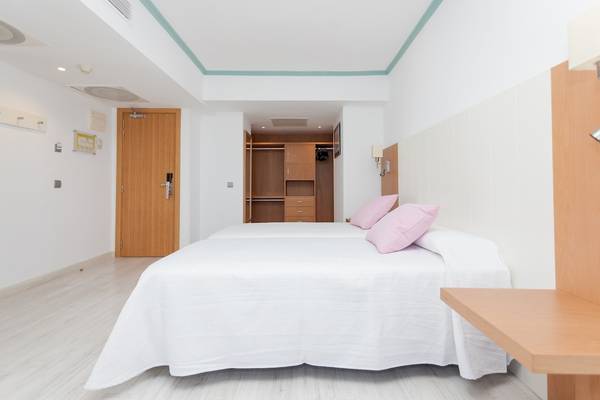 Ein Schlafzimmer im Timor Hotel mit einem Doppelbett und einem Holzschrank.