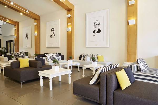 Lobby des Capo Di Corfu Hotels mit Sofas, Tischen und Kunstwerken an den Wänden.