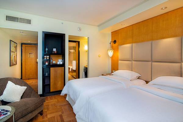 Doppelzimmer im Sheraton Abu Dhabi Hotel & Resort mit zwei Betten, Möbeln und Badezimmertür.