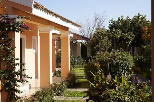 Außenansicht des Capo Di Corfu Hotels mit Gebäuden, Pflanzen und einer Hausnummer 20.