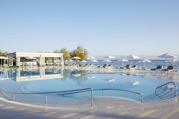 Außenpool des Capo Di Corfu Hotels mit Lounge-Sesseln und Sonnenschirmen.