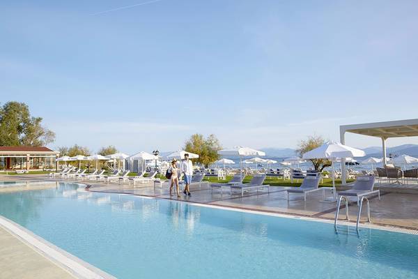 Paar am Poolbereich des Capo Di Corfu Hotels mit vielen Sonnenliegen und Sonnenschirmen