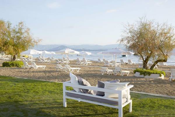 Strandloungebereich des Capo Di Corfu Hotels mit weißen Sonnenliegen und Sonnenschirmen