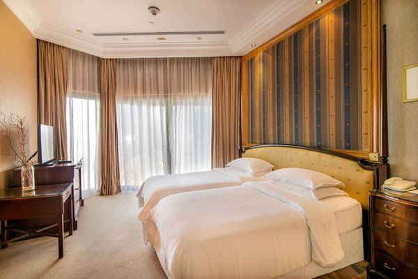 Schlafzimmer im Sheraton Abu Dhabi Hotel mit zwei Betten und großen Fenstern.