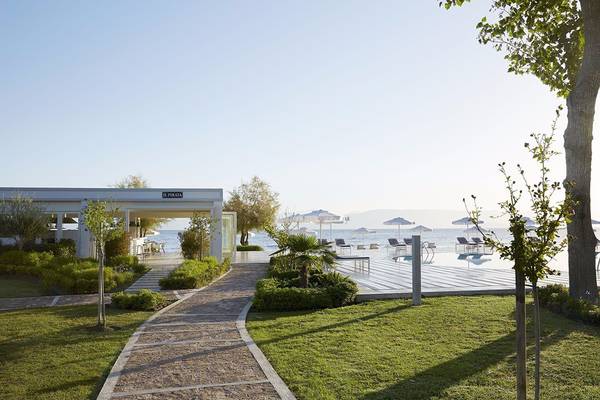 Außenbereich des Capo Di Corfu Hotels mit Pool, Sonnenliegen und Bäumen.