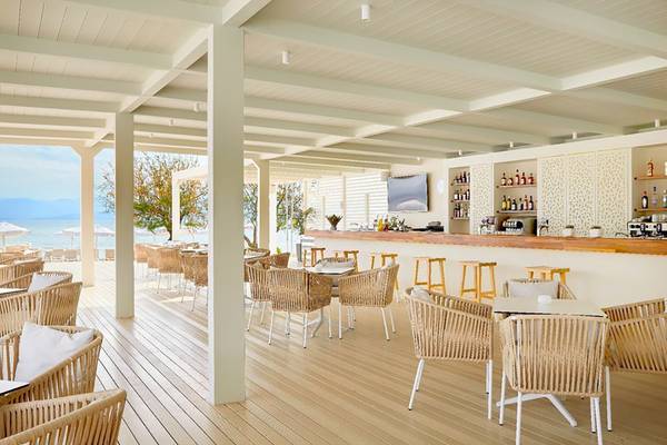 Innenbereich des Capo Di Corfu Hotels mit Blick auf eine Bar und Tische.