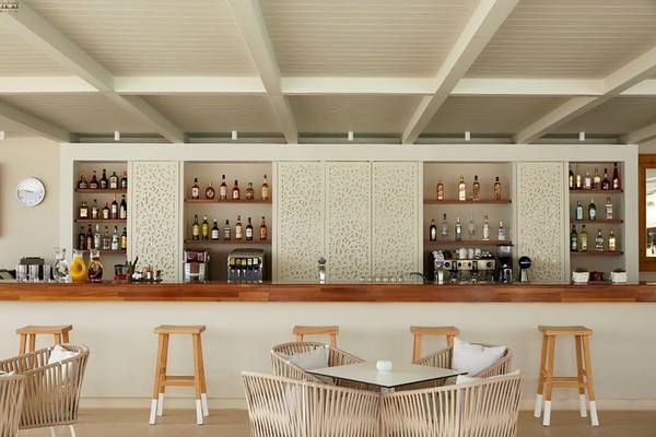 Innenansicht der Bar im Capo Di Corfu Hotel mit gepolsterten Stühlen und einer Theke voller Flaschen.