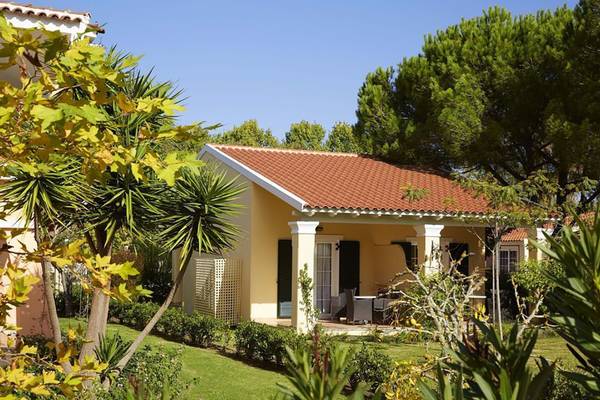 Villa des Capo Di Corfu Hotels mit rotem Dach und grünem Rasen vor blauem Himmel