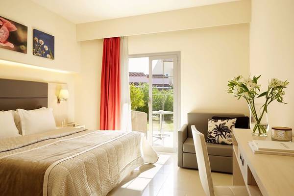 Hotelzimmer im Capo Di Corfu mit Bett, Tisch, Couch und Balkon.