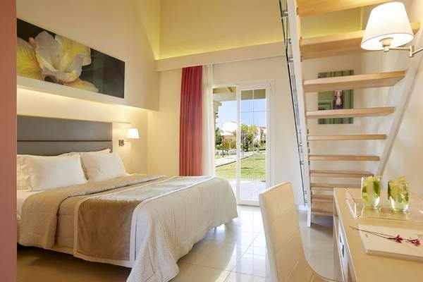 Schlafzimmer im Capo Di Corfu Hotel mit Doppelbett, Fenster und Treppe.