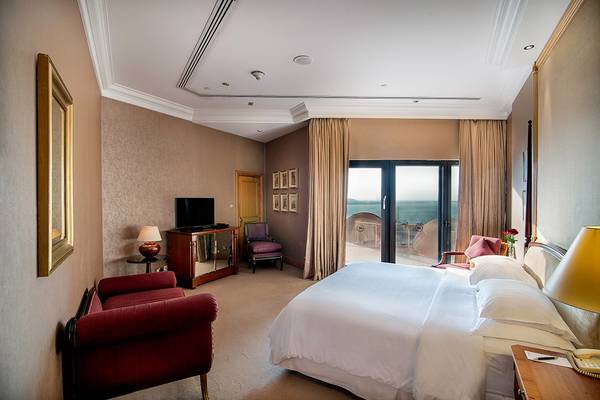 Schlafzimmer im Sheraton Abu Dhabi Hotel & Resort mit Meerblick, einem großen Bett und zwei roten Sesseln.