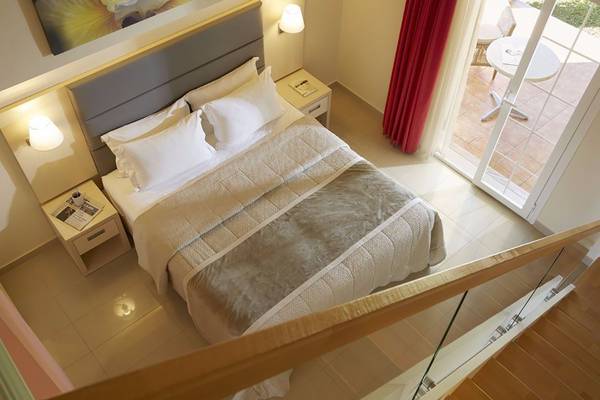 Schlafzimmer mit Balkon im Capo Di Corfu Hotel mit geräumigem Bett und Ausblick auf Terrasse.