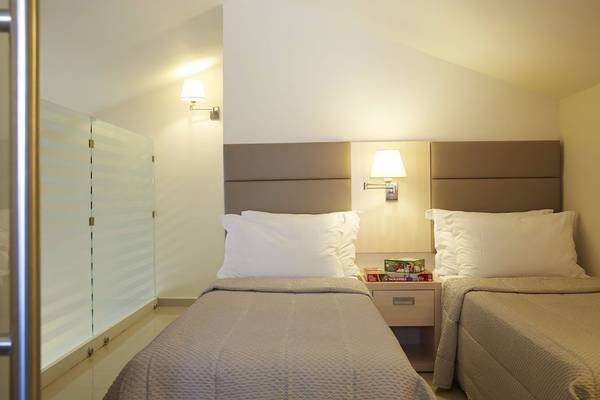 Doppelzimmer im Capo Di Corfu Hotel mit zwei Betten, Nachttischen und Wandlampen.