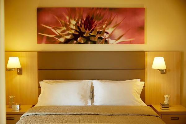Schlafzimmer im Capo Di Corfu Hotel mit Doppelbett, Nachttischen und Wandkunst.