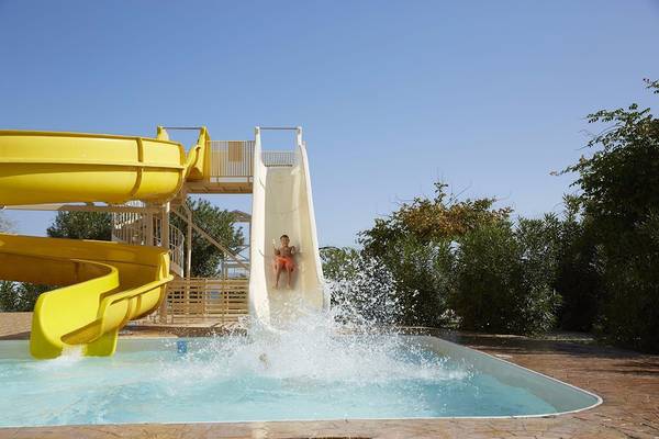 Ein Junge rutscht auf einer gelben Wasserrutsche im Capo Di Corfu Hotel.