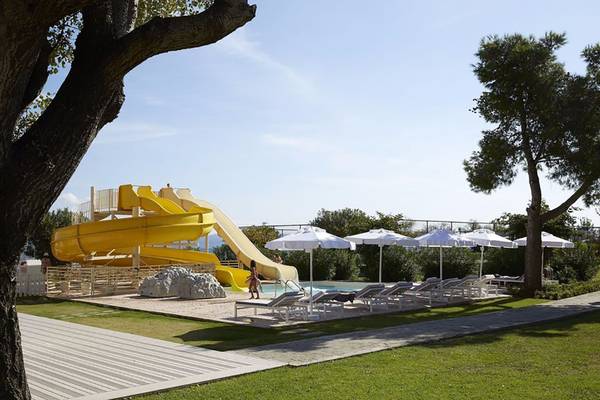 Wasserrutsche im Capo Di Corfu Hotel mit Sonnenliegen und Sonnenschirmen.