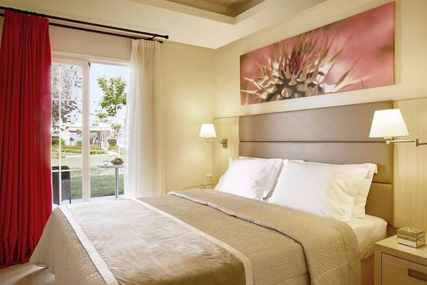 Schlafzimmer im Capo Di Corfu Hotel mit Bett, Fenstern und Dekor.