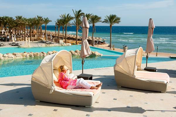Frau im Hotel The Makadi Spa liegt auf einem Liegestuhl am Pool.