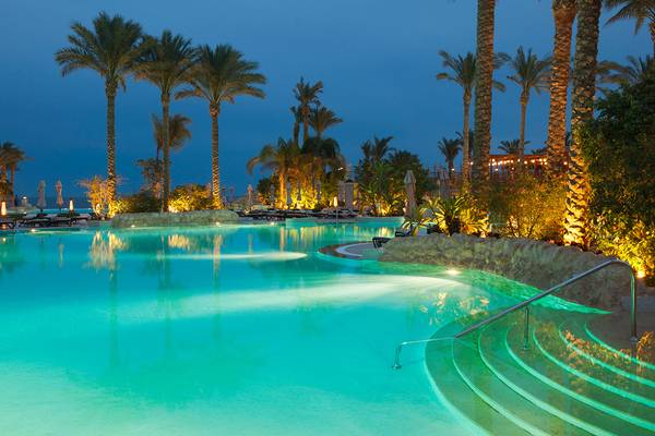 Beleuchteter Pool im Makadi Spa Hotel bei Nacht mit Palmen und Sonnenliegen
