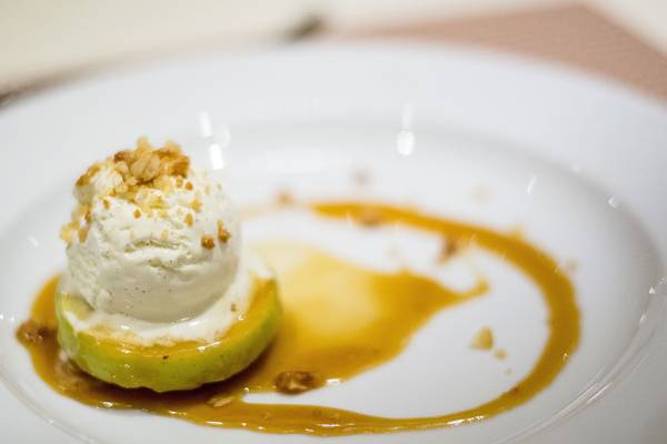Eisbedeckter Apfel auf einem weißen Teller mit Karamellsauce.