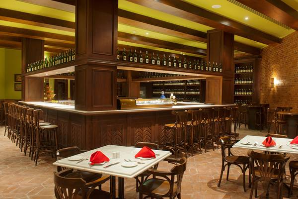 Innenansicht der Bar im Makadi Spa Hotel mit Holztischen, Stühlen und einer Theke voller Flaschen.