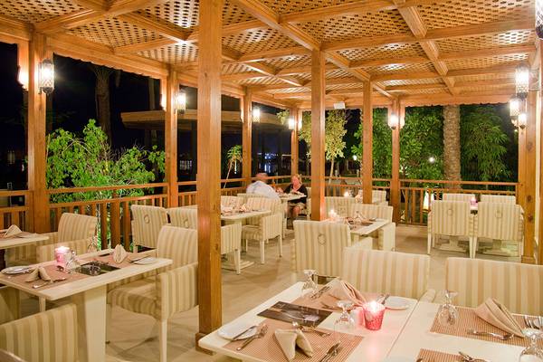 Bestuhlte Außenterrasse des Makadi Spa Hotels bei Nacht mit Blick auf zwei Personen, die an einem Tisch sitzen.