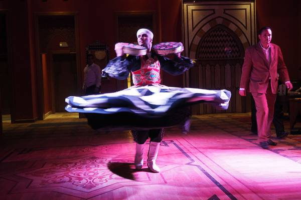 Arabischer Tänzer im Makadi Spa Hotel mit Tamburinen in der Hand, während ein Mann im Hintergrund steht.