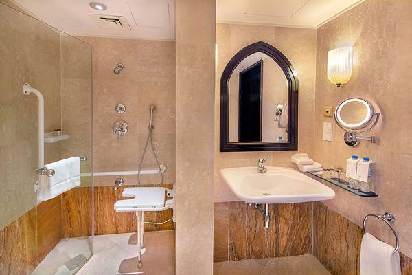 Behindertengerechtes Badezimmer im Sheraton Abu Dhabi Hotel mit ebenerdiger Dusche, barrierefreiem Sitz und Waschbecken.