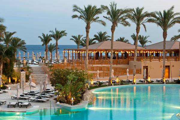 Makadi Spa Hotel Poolbereich bei Nacht mit Palmen und Sonnenliegen
