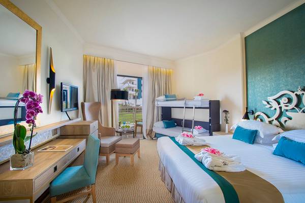 Ein elegantes Hotelzimmer im GrandResort Limassol mit zwei Betten, einem Schreibtisch und einem Spiegel.