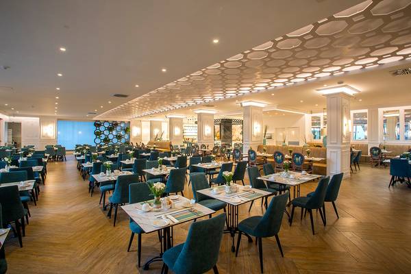 Innenansicht des Restaurants im GrandResort Limassol mit vielen gedeckten Tischen und Stühlen.