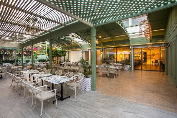 Innenbereich des GrandResort Limassol Restaurants mit grüner Dachkonstruktion und Tischstühlen.