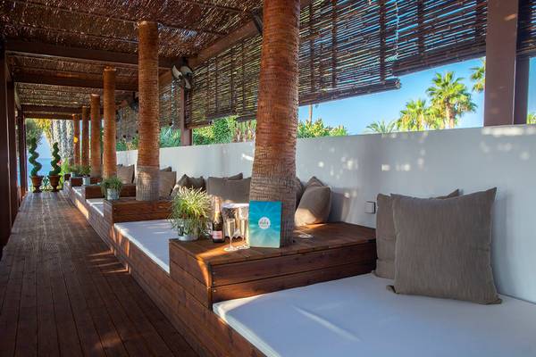 Lounge-Sofas auf der Terrasse des GrandResort Limassol mit Blick auf Palmen und Meer.