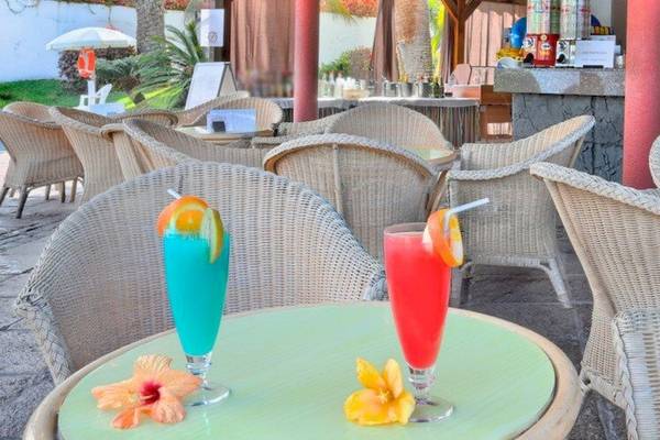 Terrasse des Bluesea Interpalace Hotels mit Tisch, Cocktails und Sonnenschirm.