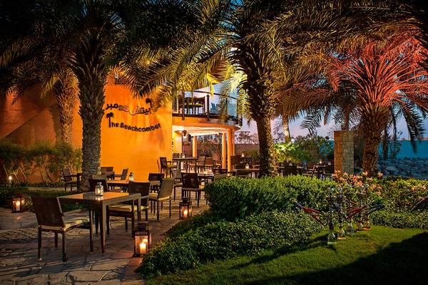 Außenbereich des Sheraton Abu Dhabi Hotel & Resort mit beleuchteten Tischen und Stühlen.