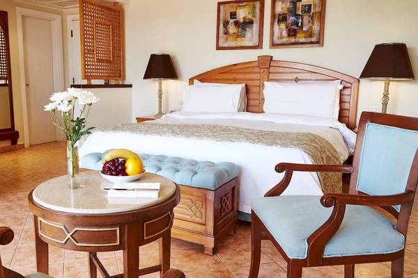 Hotelzimmer im Kempinski Hotel Soma Bay mit großem Bett, Obstschale, Blumenvase und Dekor.