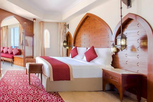Schlafzimmer im Kempinski Hotel Soma Bay mit rotem Teppich und großen Bett.
